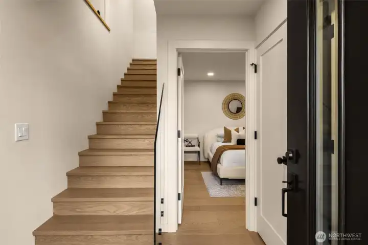 A bright and inviting foyer with soaring ceilings and designer lighting sets the tone for the rest of the residence, Features a bed and bath on the ground level, making for a perfect guest suite or office