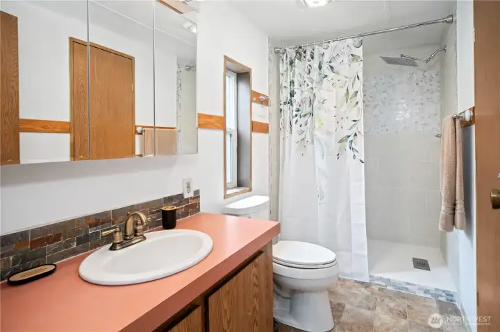 Primary bath with curb-less tiled shower and rain garden showerhead.
