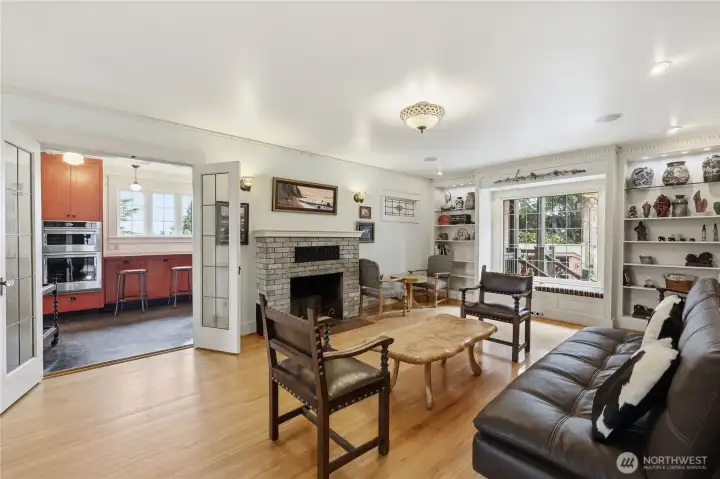 The window box with the original leaded class window looks out to the private patio.  Small leaded glass window is  original to the home. Through the 2 glass doors you enter the kitchen area. Some furniture is for sale.