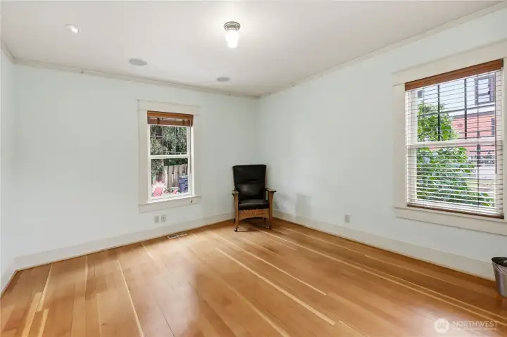 Mainfloor bedroom on the south side of the home viewing the patio and vegetable gardens. Clear Vertical Grain fir wood floors.
