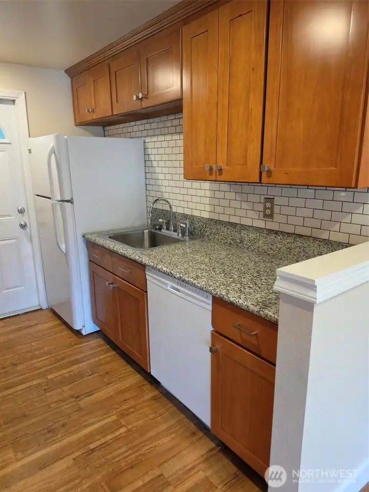 Looking at other side of galley style kitchen to back door to private yard, patio and laundry area.