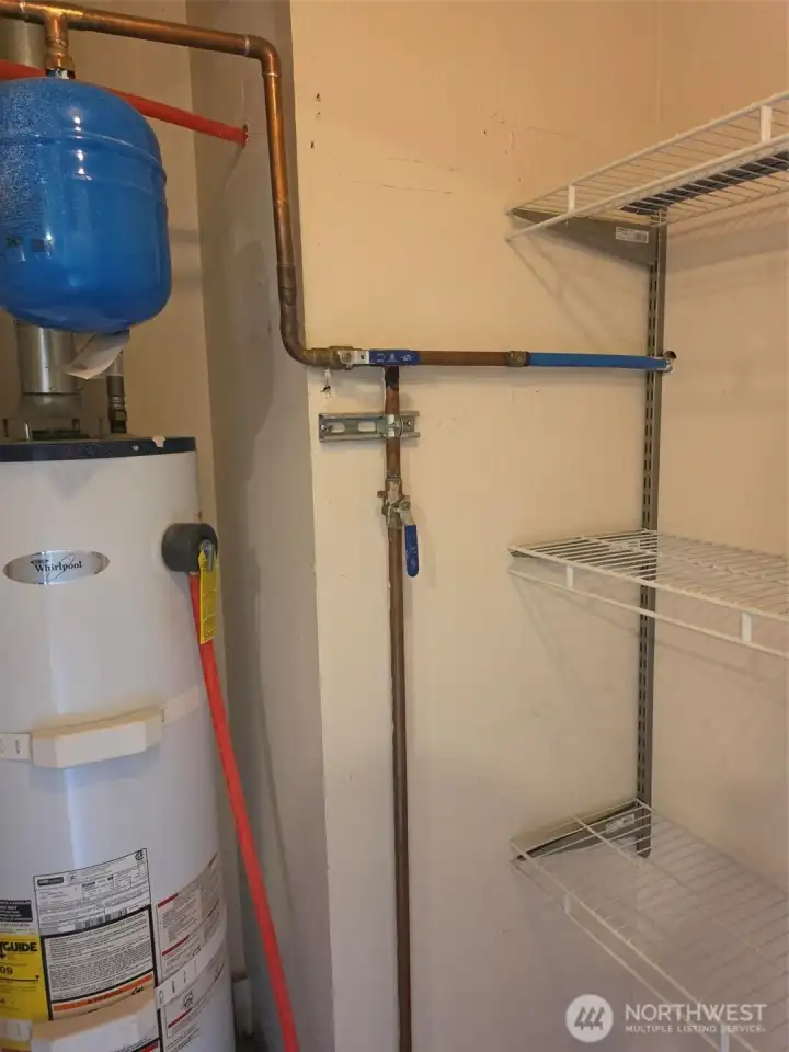 Closet with storage and hot water heater.  Hot water heater has hurricane straps and drain pan.