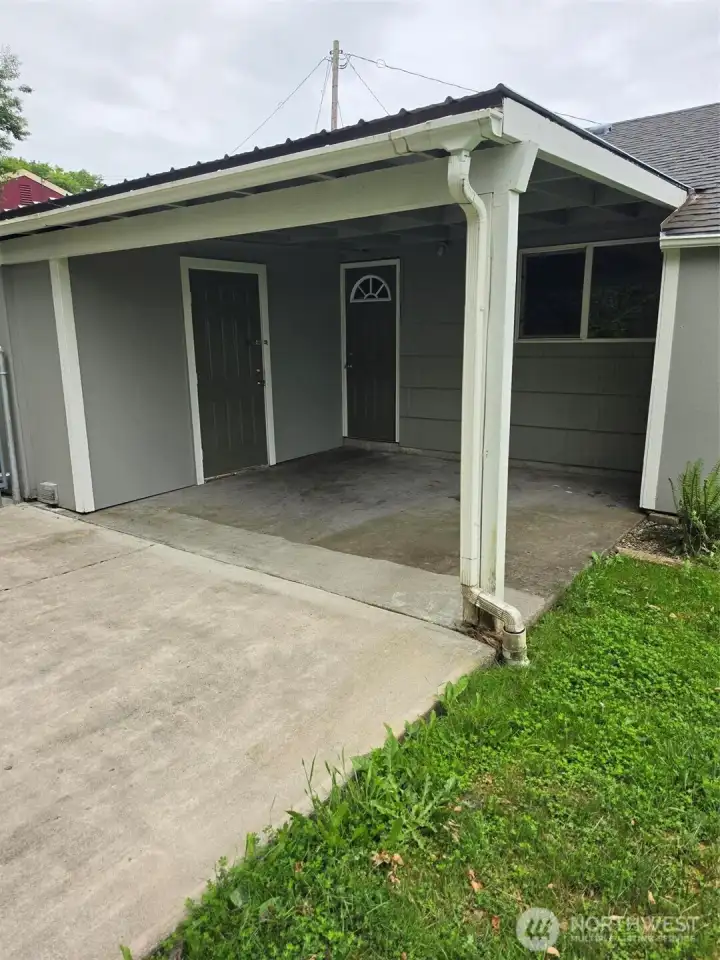 Close up of covered patio with utility room door to left and rear door into kitchen to the right