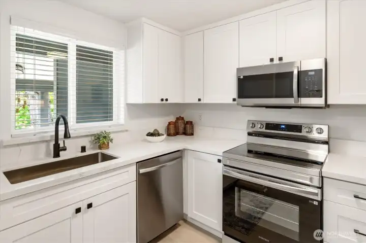 Beautifully updated kitchen featuring crisp white cabinetry, quartz countertops, stainless steel appliances, and modern finishes throughout.