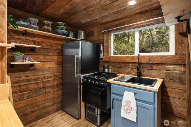 Sweet little kitchen with nice sized fridge and space to store dishes and silverware.