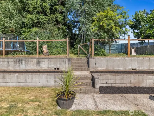 The thoughtfully designed terraced yard adds dimension and character to the outdoor space, creating distinct levels perfect for gardening, relaxing, or entertaining.