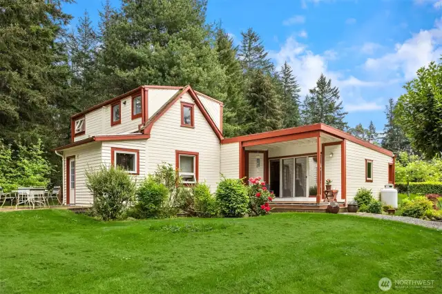 The main home sits back from the road with privacy and rolling green lawn.