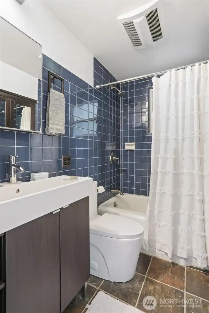 Main floor remodeled bathroom with stone tile floors and tiled walls and shower.