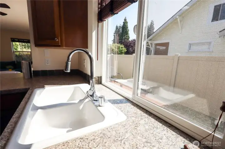 Sink with a window into the fenced backyard and patio