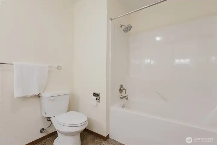 Primary en-suite 5 item bathroom: two sinks, toilet, bathtub with shower