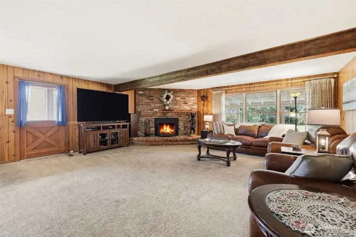 Spacious livingroom with a woodburning fireplace. Door leads out to the very large covered porch.