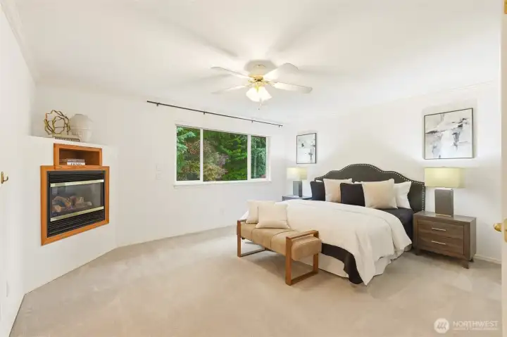 primary suite with fireplace and ceiling fan