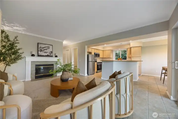 Bright and inviting open-concept living space featuring expansive windows that fill the home with natural light and frame serene lake views. The comfortable living area flows seamlessly into the dining space and kitchen, creating an ideal setting for relaxed lakeside living and entertaining. Neutral tones, updated finishes, and direct access to the covered patio enhance the warm and welcoming atmosphere.