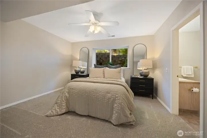 Spacious and serene bedroom retreat featuring soft natural light, neutral tones, and plush carpeting for a warm and relaxing atmosphere. Large windows frame peaceful outdoor views while the generous layout offers ample space for comfort and functionality. A bright ensuite bath and oversized closet complete this inviting primary suite.