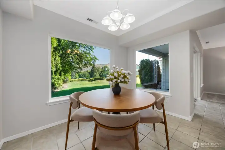 Bright and cheerful dining area surrounded by natural light and lush greenery views through oversized windows. The open layout creates an inviting space for casual dining and entertaining, while clean lines, neutral finishes, and contemporary lighting enhance the fresh, airy feel of the home.