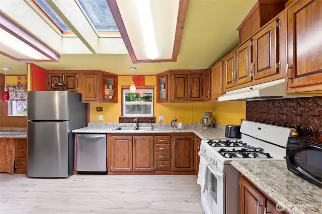 The kitchen features a stainless steel fridge and dishwasher, and a gas stove.