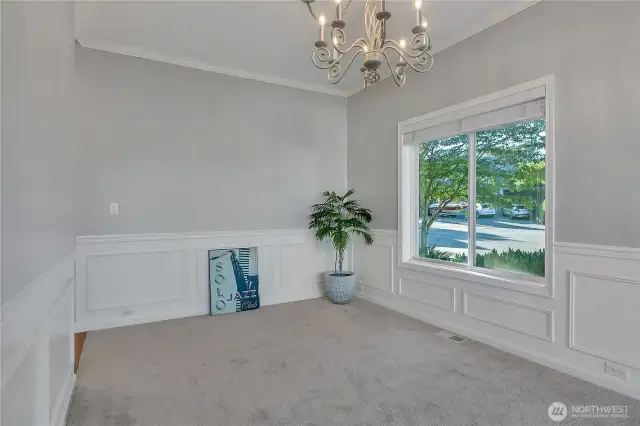 The formal dining room features custom molding and a chandelier-along with a large window for ambient light during the day.