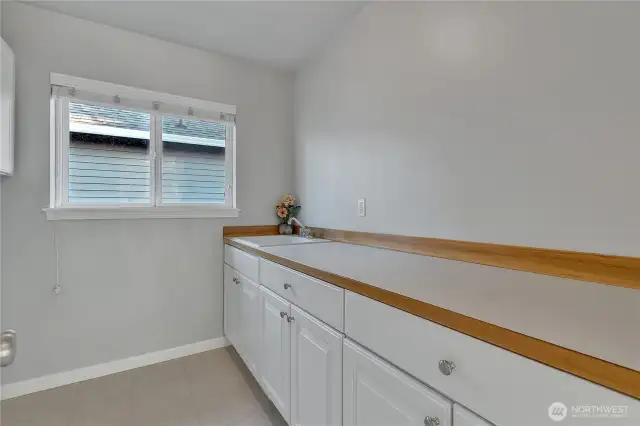 Laundry room, which is on the second floor, where all the bedrooms are located. It has ample cabinet storage and a counter with a sink.
