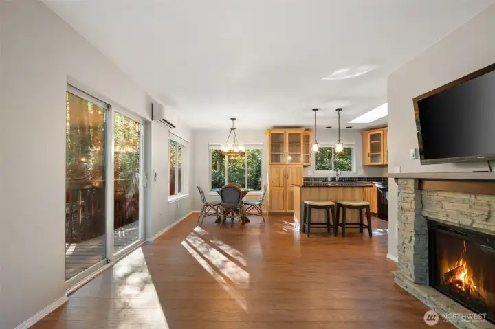 Living room toward dining and kitchen, with large slider to private deck overlooking wooded wonderland.  Photo taken from just inside entry door.  Electric fireplace on right.