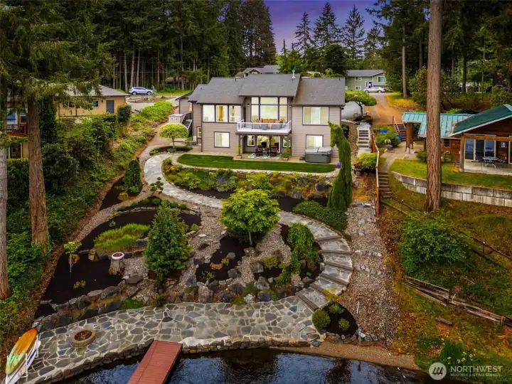 The layered mix of mulch beds, mature low-profile plantings and river rock creates beautiful texture and dimension while still keeping the overall design wonderfully low maintenance and view-friendly. And there is still room left for the next owner to personalize the landscaping with their own flowers, shrubs or seasonal color if they want to put their own stamp on the property over time. The use of river rock throughout also helps tremendously with drainage while adding that clean polished waterfront aesthetic that fits the home so well. Instead of sinking into muddy lake-bottom muck while trying to swim or launch kayaks, the area just off the bulkhead features a pea gravel lake floor, making the waterfront experience dramatically cleaner, more comfortable and much more enjoyable for swimming and water access.