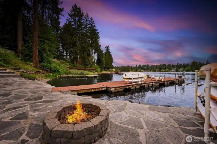 The built-in fire pit sits right at the water’s edge on the flagstone patio creating the ultimate gathering spot for sunset drinks, late-night conversations and aggressively over-toasted marshmallows. From this angle, you can also appreciate how thoughtfully designed the shoreline access is, with those extra-wide low-profile steps gently connecting the lawn down toward the waterfront without feeling steep or awkward to navigate. And then there is the dock situation, which is seriously impressive. Composite Trex decking keeps maintenance lower while giving the dock a clean polished look, and at 42 feet long with an 8x20 platform at the end plus a 10-foot connecting ramp, there is plenty of room to fully enjoy the lake lifestyle. The 4,500-pound boat lift stays with the property too, which is a huge bonus, along with the jet ski dock. And yes, the jet ski itself may even stay if the buyers want a little project with a potentially very fun payoff.