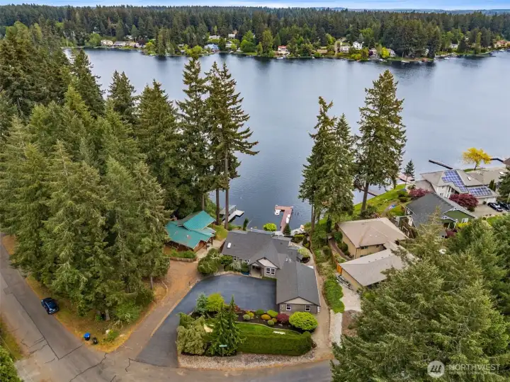 This aerial really highlights how intelligently the entire property was planned. From the street side, mature cedar trees create a wonderful sense of privacy and separation, giving the home that tucked-away peaceful feeling the second you arrive. But then as the property opens toward the lake, the landscaping intentionally drops to a much lower profile so the water views stay completely unobstructed from the living spaces and outdoor entertaining areas. It is such a thoughtful balance between privacy and maximizing the setting. And somehow the storage situation in this home just keeps getting more impressive too. The garage includes pull-down attic stairs leading to storage spanning the full width of the garage overhead, plus there are additional interior storage areas not even shown in the photos. There is even full-height crawlspace storage below the home, which is the kind of thing people wildly underestimate until they suddenly need a place for holiday décor, camping gear and more.