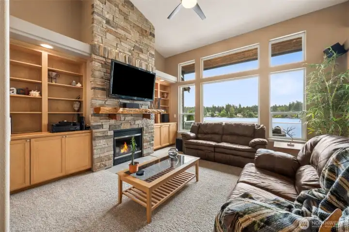 This fireplace is having a moment, and frankly it deserves one, wrapped in richly layered stone stretching all the way to the top of the vaulted ceilings, it anchors the entire living room with this incredible mix of warmth and scale. The tones are fantastic too, creamy neutrals, weathered grays, caramel undertones, all tied together with a stunning live-edge wood mantel that adds just enough organic texture to keep the room from feeling overly formal. On both sides, illuminated built-ins create a library-meets-display-gallery vibe with lower cabinetry ready to hide board games, blankets and all the little things real life brings with it. Then the giant lake-facing windows step back in to remind you Long Lake is still the star of the show. Add the ceiling fan plus brand-new 2025 gas furnace, HVAC and heat pump system, and this home delivers beauty with the kind of practical peace of mind.