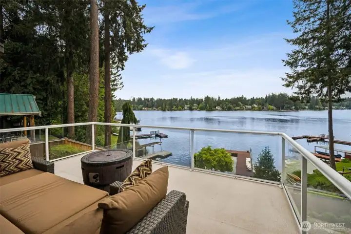 This deck was designed for maximum lake appreciation. The glass-panel railings are wonderfully unobtrusive, letting the water, sky and shoreline stay visually front and center instead of blocking everything behind bulky balusters. Combined with the Trex composite decking, the whole space feels polished, durable and refreshingly low maintenance. And because the deck is completely open overhead, you get the full sensory experience of waterfront living, sunrise colors reflecting across the lake, warm midday sun, evening breezes and star-filled skies overhead at night. The east-facing exposure gives this deck a really comfortable rhythm throughout the day too, bright and cheerful in the mornings while the home itself helps provide some relief from stronger afternoon heat later on. And underneath, the waterproof decking system protects the covered patio below so both levels of outdoor living space stay functional, comfortable and ready for entertaining year-round.