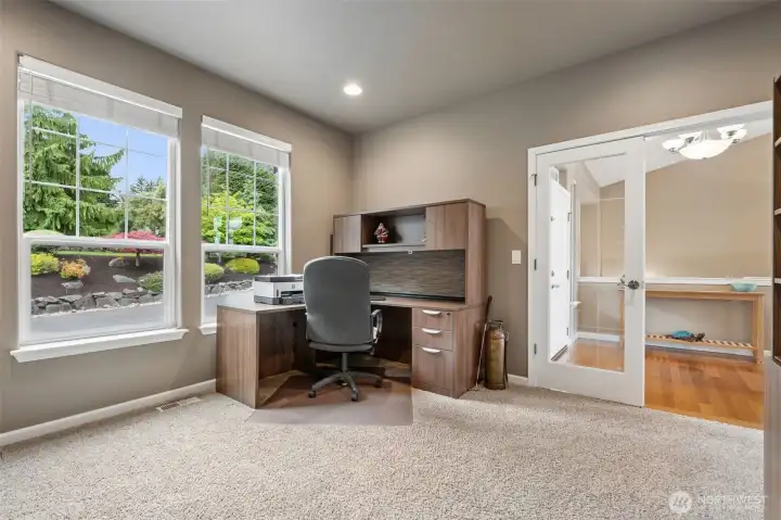 Every good lake house needs a room that can shape-shift a little, and this den absolutely understands the assignment. The French doors with glass paneling give it a polished, intentional feel right off the foyer, while the two large windows overlooking the front drive keep the room bright without sacrificing privacy. Warm taupe carpeting and richer neutral tones make the space feel especially comfortable and tucked in. With the three-quarter bath sitting immediately beside it on the main floor, this easily becomes an ideal guest room setup for anyone wanting stair-free living. Flexible spaces like this are worth their weight in gold.