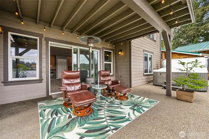 One of the biggest disappointments in many waterfront homes is discovering the lower covered patio is dark, damp or visually boxed in while all the “real” outdoor living happens upstairs. Not here. This space still captures a huge uninterrupted lake view & the upper deck has been fully waterproofed, which is why you can comfortably have actual upholstered leather seating down here w/o constantly worrying about water dripping through overhead. Huge difference. The shades on both sides of the patio stay with the home, giving you added privacy, glare control and protection from afternoon sun whenever you want it, while the string accent lighting creates that warm glowy ambiance everybody secretly hopes their outdoor spaces will have. Add the hot tub, gorgeous HardiePlank siding wrapping the full exterior and those wood-wrapped windows bringing warmth to the architecture, & suddenly this lower patio starts feeling less like “bonus space” & more like a second luxury waterfront Living Room.