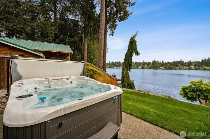 The hot tub sits perfectly positioned to soak in the water view while the gently sloping lawn rolls naturally down toward the beachfront below, creating such an easy, inviting connection to the lake. And nearby, the outdoor shower is ready for rinsing off sandy feet, lake water, sunscreen or post-swim chaos before heading back inside. But honestly, the best part may be that the hot tub is completely open to the sky. No roof cutting off the stars, no enclosure separating you from the weather and sounds around you. Because sitting in steaming hot water while rain falls around you or snowflakes drift down quietly over the lake? That is elite Pacific Northwest energy right there.