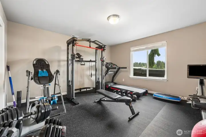 This lower-level room is currently living its best life as a home gym, but the flexibility here is fantastic. At approximately 14x17, the space is large enough to easily transition back into a true bedroom while still leaving room for seating, desks or hobby setups depending on what life calls for next. And yes, even down here you still get lake views through the oversized window because apparently this house refuses to waste a single good sightline. The gym flooring and wall mirrors will stay with the home, creating all kinds of possibilities beyond fitness too. Playroom, yoga studio, music room, dance practice space, creative studio, gaming lounge, there is enough size and separation here to really make the room your own. The flooring even brings a little sound-softening benefit that works beautifully for activities where you do not necessarily want noise bouncing all over the house. Flexible spaces like this are gold because they evolve right alongside the people living in them.