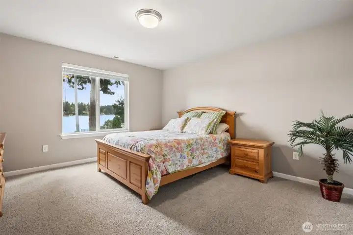 This spacious lower-level room stretches approximately 13x17 and feels bright, calm and surprisingly serene thanks to the oversized window pulling in beautiful water views from Long Lake. The warm neutral wall tones and soft carpeting continue the cohesive palette carried throughout the home, giving the entire lower level the same welcoming atmosphere as the main floor instead of feeling like an afterthought. And because this bedroom sits opposite the gym/flex room on the other side of the lower level, the split layout creates fantastic privacy for guests, teenagers, extended stays or multigenerational living.