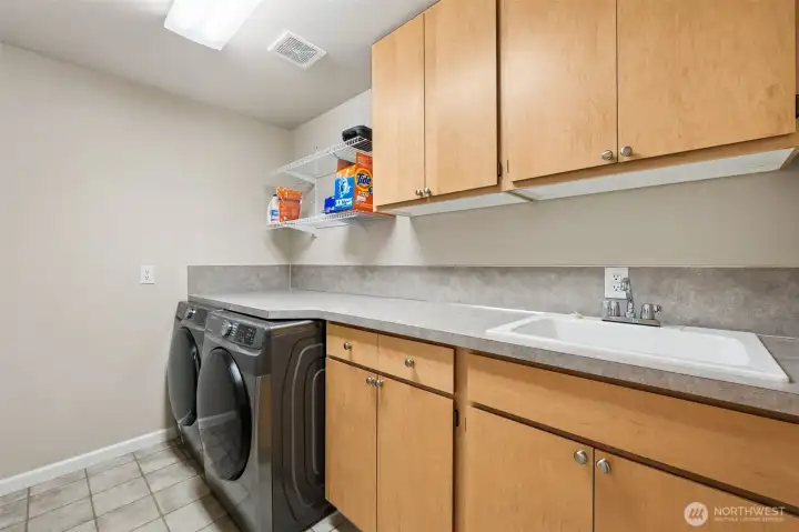 In the laundry room on the lower level, huge amounts of cabinetry, extended countertop workspace, open shelving, utility sink and enough storage to make even the most disorganized person suddenly believe they could become “someone who folds things immediately.” The high-efficiency washer and dryer tuck neatly beneath the long counter, giving you actual usable workspace instead of forcing you to balance laundry baskets on top of appliances, and throughout this home, the storage situation just keeps getting more impressive. Closets, cabinetry, built-ins, hidden spaces, this house was clearly designed by somebody who understood that people actually own things and occasionally want them out of sight. There is also a central vacuum with hose for the house too!