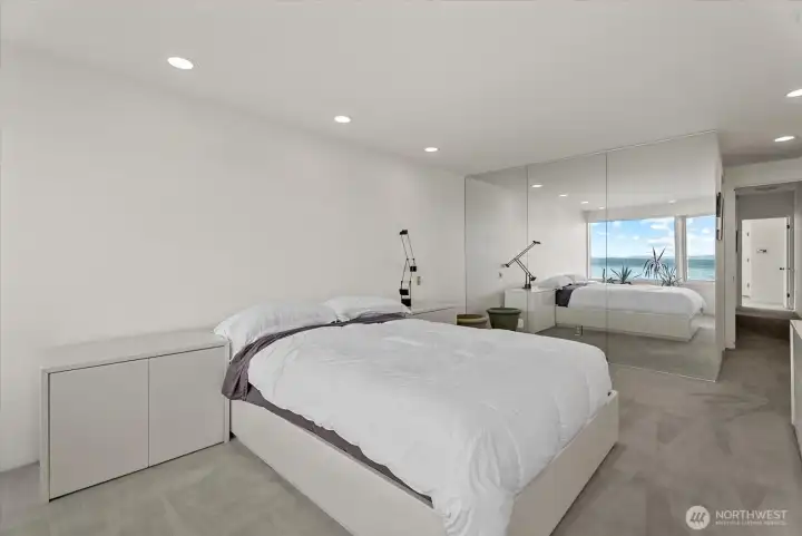 Spacious primary suite with water views and extensive mirrored closet storage. Spacious primary suite with water views and extensive mirrored closet storage.