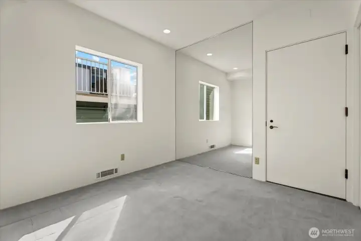 Bedroom with mirrored closet doors and natural light. Bedroom with mirrored closet doors and natural light.