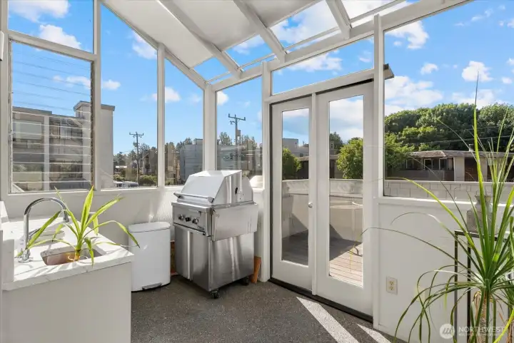 Glass-enclosed entertaining space with built-in grill and deck access. Glass-enclosed entertaining space with built-in grill and deck access.