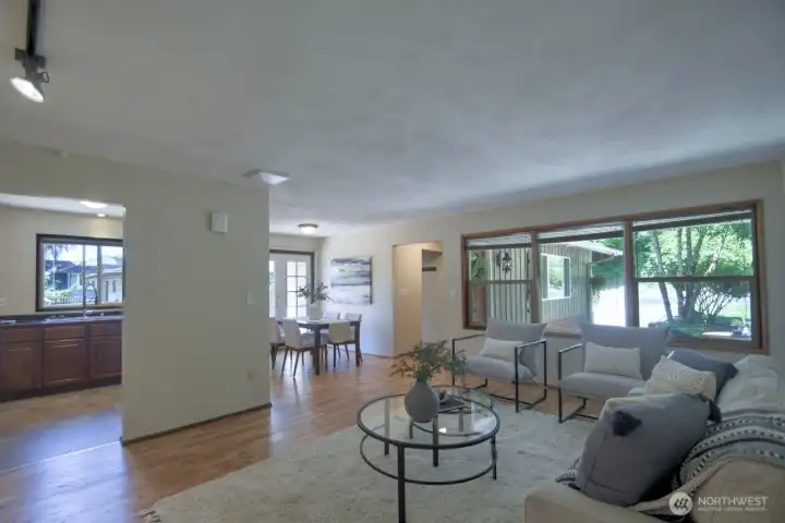 Large picture windows frame the outdoor naturescape and brighten the home with natural light. Notice the easy flow from the living room to the dining room and kitchen.