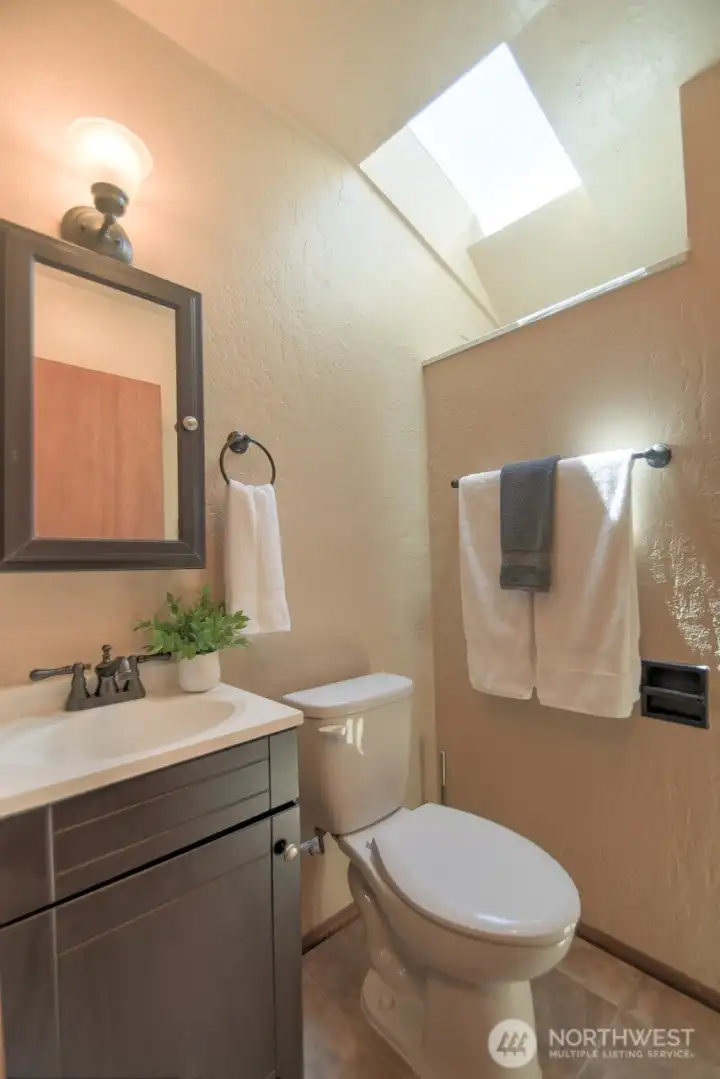 Three-quarter bathroom located near the family room made sunny and bright by the skylight.