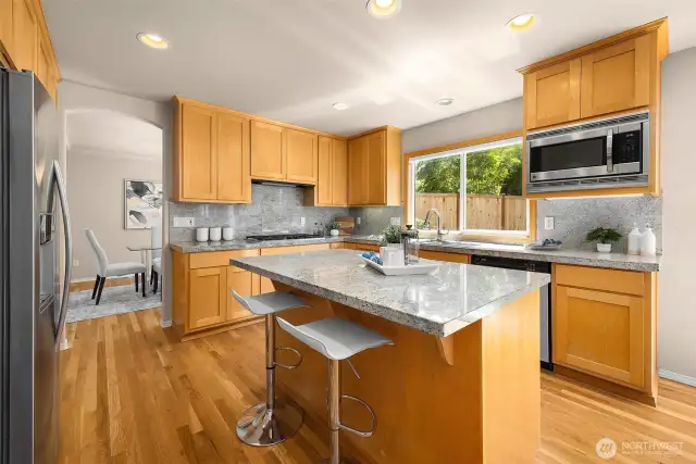 Sunny kitchen is equipped with double ovens (at left), gas range, granite counters & ample storage space. Microwave is brand new.
