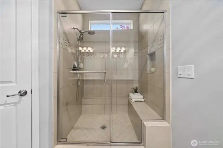 Fully tiled shower with a convenient bench and handy niche.