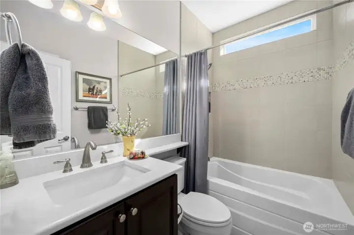 Guest bath with Quartz counters, upgraded tub with tile surround and tiled flooring.