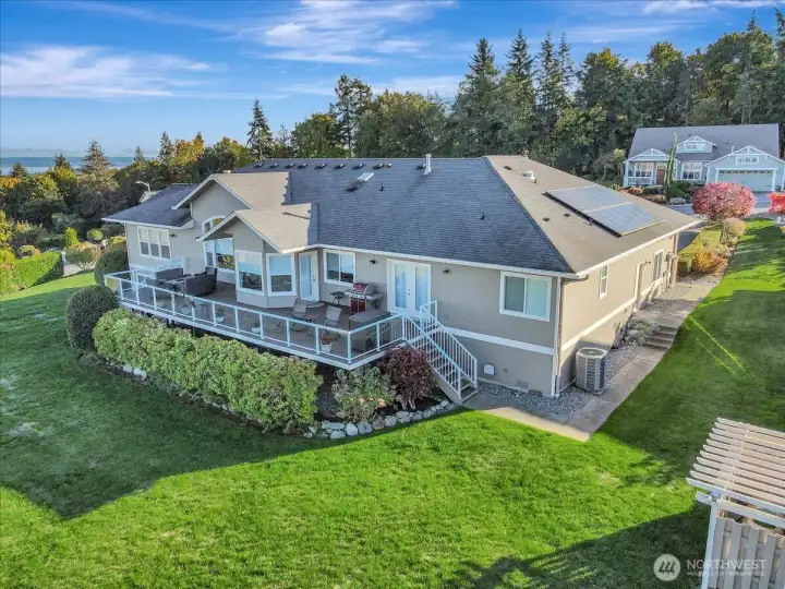 A view of the back of the house.  Two sets of stairs lead down into the yard from the spacious deck.