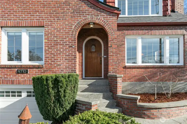 Imagine fragrant roses blooming by the graceful arched brick covered entry.