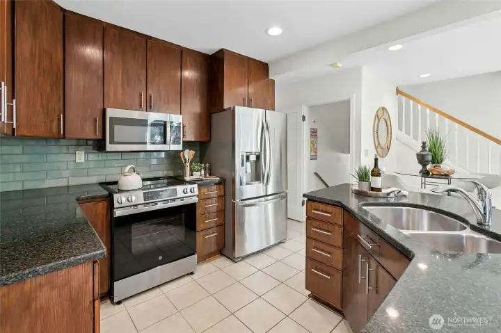 Chefs delight in this spacious modern kitchen with granite countertops, glass tile backspace, stainless steel appliances, and tons of storage space.