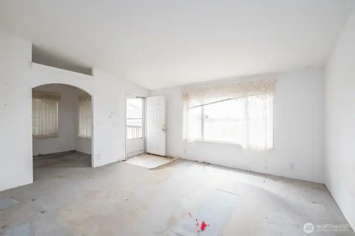 Entry way and living room with a peak into the office.  Needs flooring, paint and window treatments