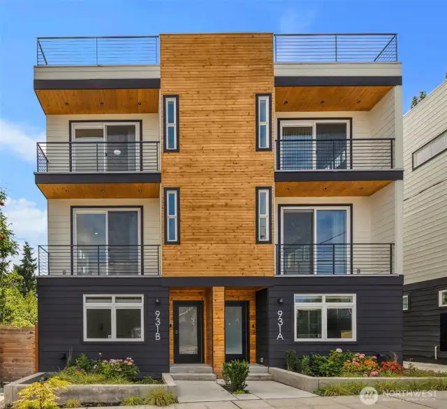 Lovely modern architecture with warm cedar accents, lush landscaping, and a welcoming covered entry — perfectly framed by wide sidewalks for a friendly neighborhood feel.