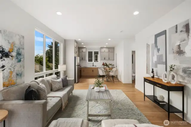 Sunlit living space flows seamlessly into the dining area and kitchen, with oversized windows framing treetop views and inviting the outdoors in.