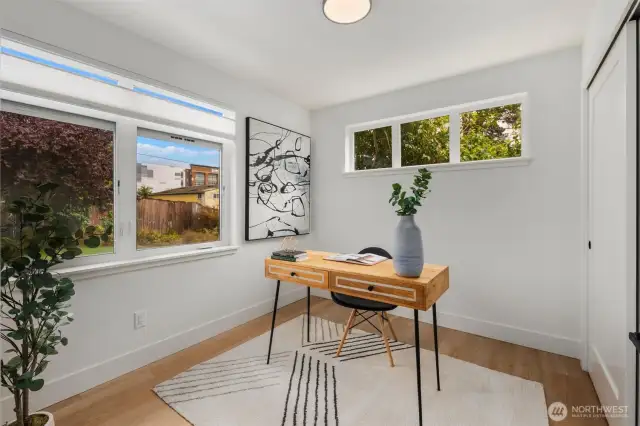 Bright main floor bedroom with dual exposures, offering a peaceful view of greenery and plenty of natural light.