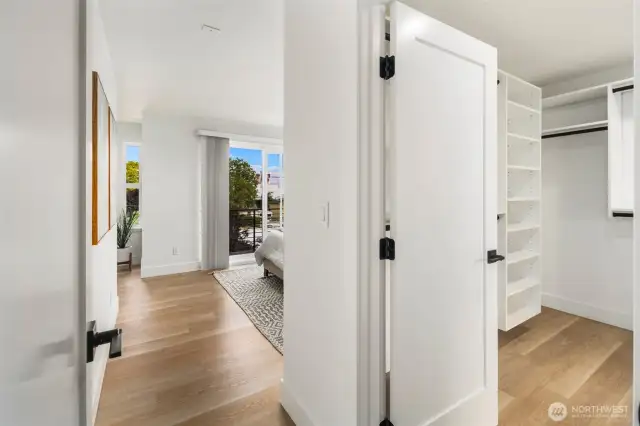 Step into the sunlit primary suite, complete with warm wood floors and a spacious walk-in closet.